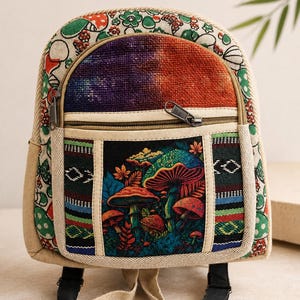 Peut inclure: Un petit sac à dos avec un motif de forêt de champignons sur la poche avant. Le sac présente une texture en tissu avec un imprimé multicolore de fleurs et de champignons sur les côtés et le dessus, ainsi qu'un compartiment avant zippé.
