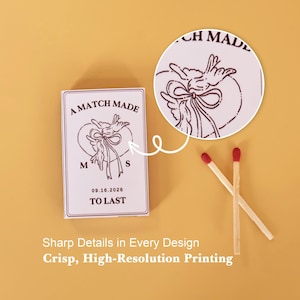 May include: A rectangular matchbox with white casing and dark maroon ink printing. The design features two birds holding a ribbon, the text A MATCH MADE TO LAST, the initials M and S, and the date 09.16.2026. Two wooden matches with red tips lie nearby.