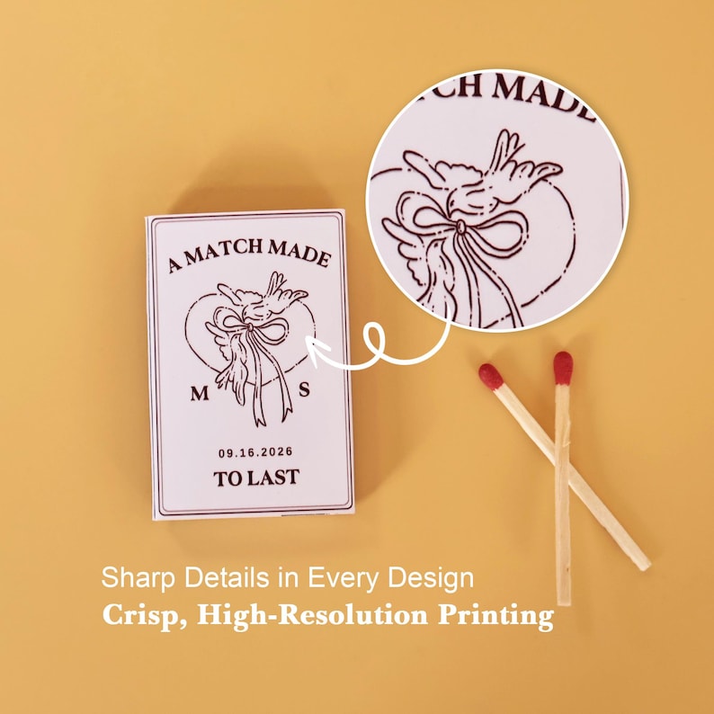 May include: A rectangular matchbox with white casing and dark maroon ink printing. The design features two birds holding a ribbon, the text A MATCH MADE TO LAST, the initials M and S, and the date 09.16.2026. Two wooden matches with red tips lie nearby.
