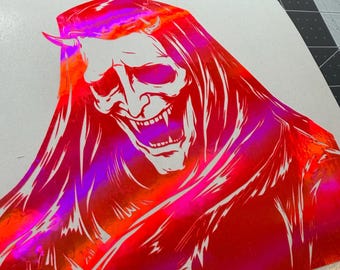 May include: A holographic vinyl decal featuring a stylized illustration of a horned demon with long hair and an open-mouthed expression. The design uses vibrant red, orange, and magenta color shifts that change appearance depending on the light angle.