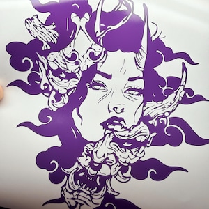 May include: A purple and white graphic illustration of a woman's face with a demon mask. The artwork features intricate details, including horns, flowing hair, and cloud-like shapes. The design is a bold, two-tone image.