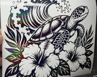 May include: A holographic decal featuring a sea turtle swimming in front of a large crashing wave, surrounded by two large hibiscus flowers and tropical leaves. The design uses black lines and a shimmering, multi-colored glitter effect.