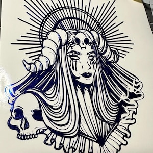 May include: A black and white illustration of a woman with horns and a skull. She is wearing a flowing gown and has a halo of light around her head.