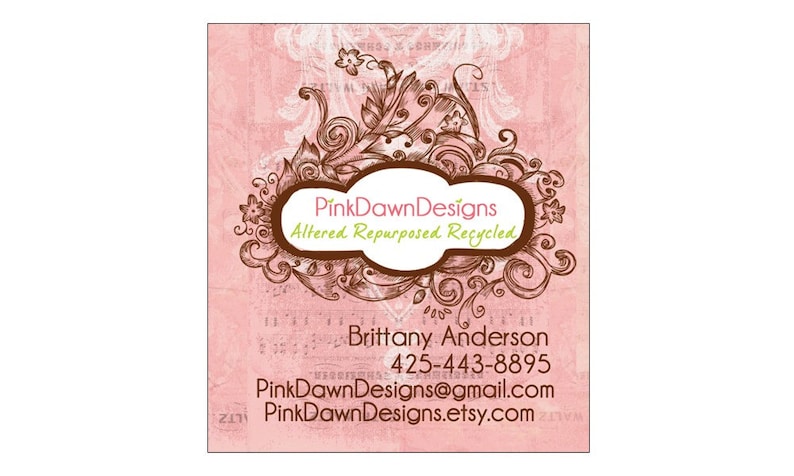 May include: PinkDawnDesigns business card with a pink background and brown floral design. The text reads "PinkDawnDesigns Altered Repurposed Recycled" and includes contact information for Brittany Anderson.
