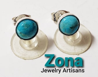 May include: A pair of silver stud earrings with turquoise stones. The earrings are on a white background with the text "Zona Jewelry Artisans".