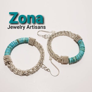 May include: A pair of silver hoop earrings with turquoise stones. The earrings are made of a silver chain and have a turquoise stone design. The earrings are called "Zona Jewelry Artisans".
