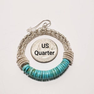 May include: Silver hoop earrings with a turquoise bead design. The earrings are large enough to fit over a US quarter.