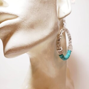 May include: Silver hoop earrings with turquoise beads. The earrings are large and have a woven design.