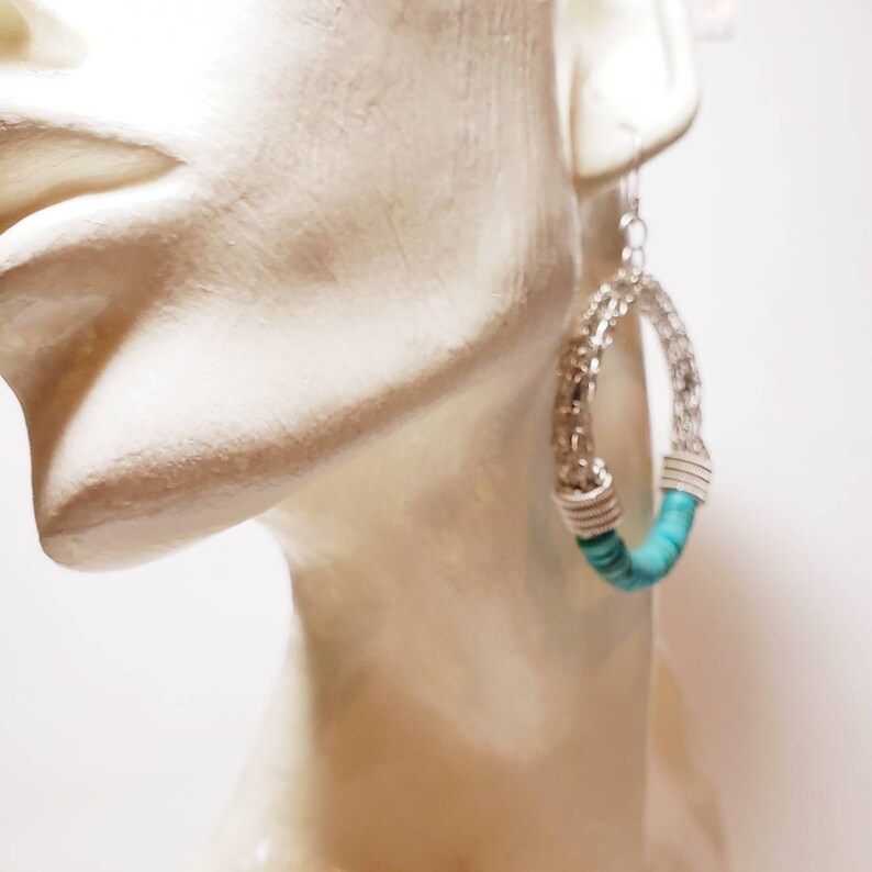 May include: Silver hoop earrings with turquoise beads. The earrings are large and have a woven design.