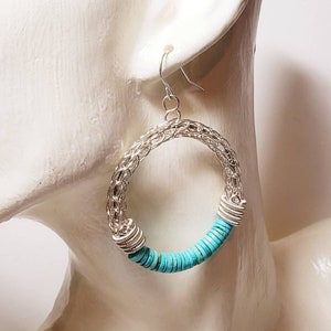 May include: Silver hoop earrings with a turquoise bead accent. The earrings are large and have a delicate wire design.