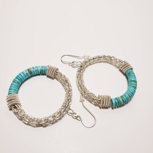 May include: A pair of silver hoop earrings with turquoise beads. The earrings are made of a silver chain and have a turquoise bead design.