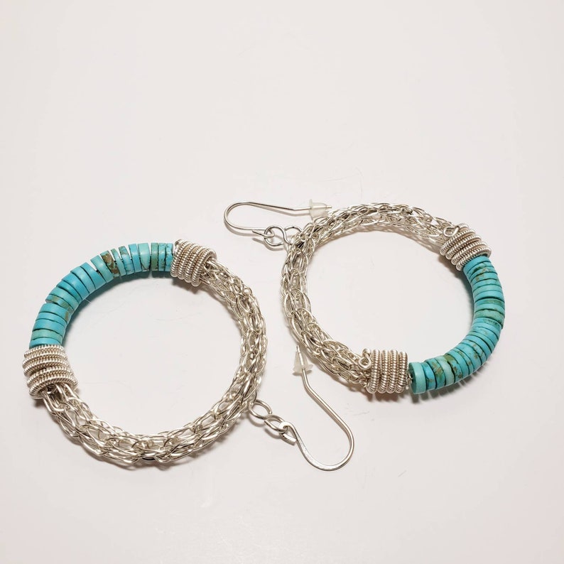 May include: A pair of silver hoop earrings with turquoise beads. The earrings are made of a silver chain and have a turquoise bead design.