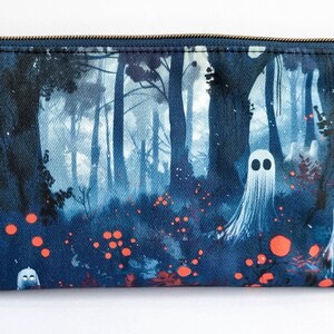 Op de afbeelding: Een donkerblauwe etui met ritssluiting. De etui heeft een boslandschap met witte spookfiguren en oranje gloeiende bollen. Het ontwerp is gedrukt op de stof, waardoor een grillige en spookachtige esthetiek ontstaat.