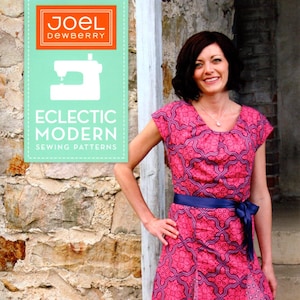May include: A sewing pattern for a vintage flutter dress with a pink and purple floral print. The pattern includes step-by-step instructions and a full-size pattern. The pattern is from Joel Dewberry's Eclectic Modern Sewing Patterns collection. The pattern number is JDOO5VE.