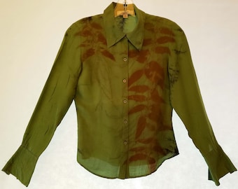 May include: A green long-sleeved button-down shirt with a brown leaf print. The shirt has a collar and long sleeves with bell cuffs.