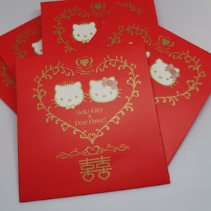 May include: Red wedding envelopes with gold lettering and a Hello Kitty and Dear Daniel design. The envelopes feature a gold heart with the Chinese character for double happiness.