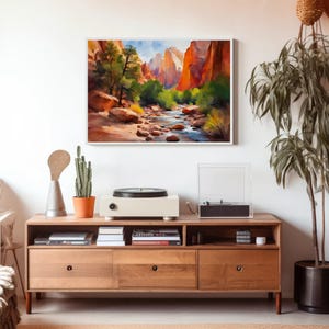 May include: A framed watercolor painting of a canyon landscape with a river, trees, and mountains. A wooden media console with a record player, cactus, and decorative items sits below the painting.