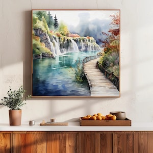 May include: Watercolor painting of a scenic landscape featuring a waterfall cascading into a turquoise lake. A wooden boardwalk extends into the water, surrounded by lush greenery and trees. The artwork is framed in a wooden frame.