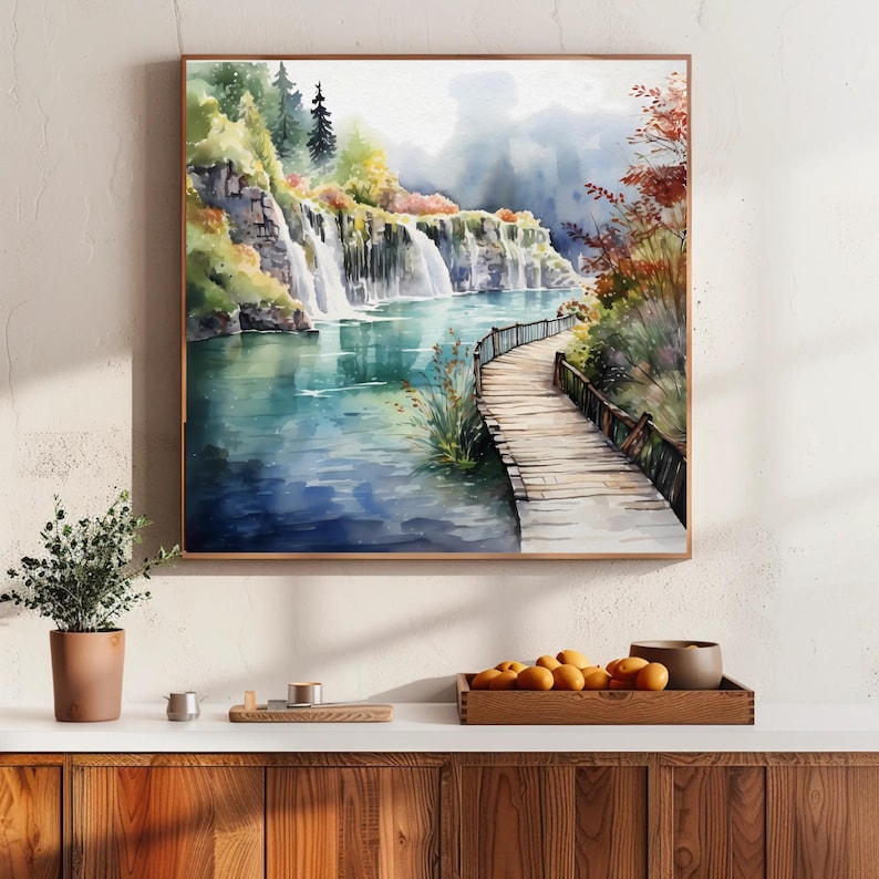 May include: Watercolor painting of a scenic landscape featuring a waterfall cascading into a turquoise lake. A wooden boardwalk extends into the water, surrounded by lush greenery and trees. The artwork is framed in a wooden frame.