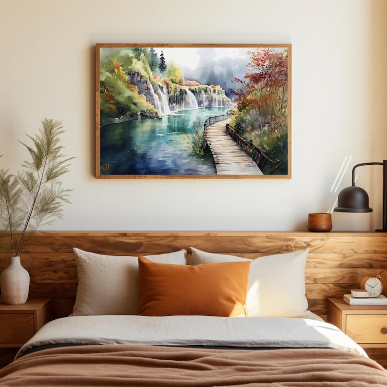 May include: A framed watercolor painting of a waterfall scene with a wooden walkway. The artwork features a vibrant color palette of blues, greens, and browns, with a wooden frame. The painting is displayed above a bed with pillows and a wooden headboard.