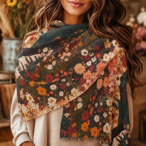 May include: A floral scarf with a dark background and a variety of colorful flowers in shades of red, orange, and white. The scarf is draped over the shoulders, showcasing the intricate floral pattern. The scarf appears to be made of a soft, lightweight material.