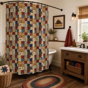 May include: A patchwork shower curtain with a mix of red, blue, and yellow squares hangs in a bathroom. The curtain is paired with a matching oval rug and a wooden vanity. A framed picture of a barn hangs on the wall.