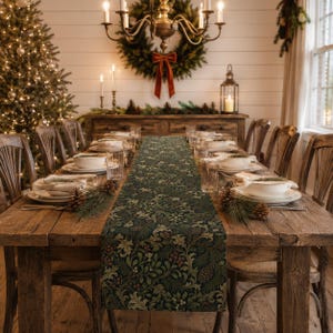 May include: A long rectangular table runner featuring a dark green background with a dense botanical pattern of oak leaves, pine needles, and small red berries. The runner is centered on a rustic wooden dining table set with white plates.