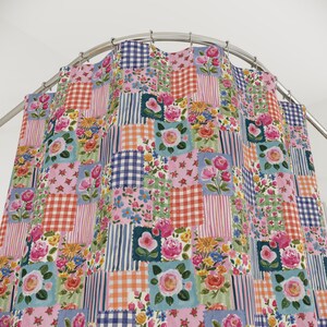 May include: A shower curtain featuring a patchwork design of floral patterns, pink roses, blue and white gingham checks, and red and white checkered squares. The curtain hangs from a curved silver metal rod with circular metal rings.