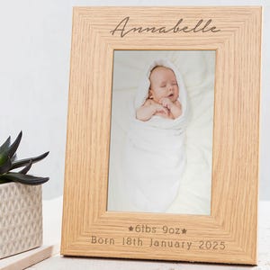May include: A wooden photo frame with a light brown finish. The frame has a photo of a baby inside and is engraved with the name "Annabelle", the baby's weight and date of birth: "*6lbs 9oz* Born 18th January 2025".
