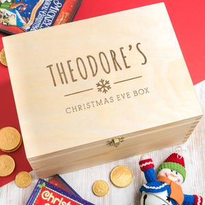 May include: A wooden Christmas Eve box with a personalised inscription that reads "Theodore's Christmas Eve Box" with a snowflake design.