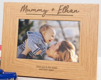 May include: A wooden photo frame with a light brown finish. The frame has a photo of a mother holding her baby. The frame is engraved with the text "Mummy + Ethan" and "I love you to the moon and back again."