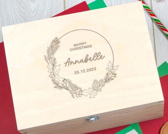 May include: A wooden box with a hinged lid, personalised with the text "Merry Christmas Annabelle 25.12.2023" in a circular wreath design. The box is light brown and has a metal clasp.