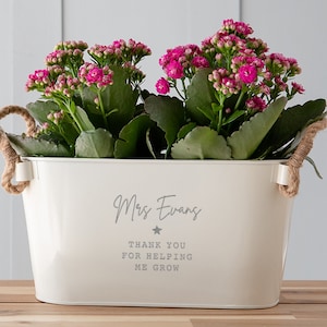 May include: White metal planter with rope handles, filled with pink kalanchoe plants. The planter is personalised with the text "Mrs. Evans Thank you for helping me grow" and a small star.