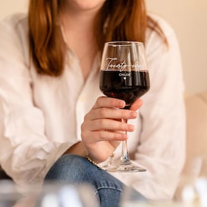 Puede incluir: Una copa de vino de vidrio transparente con el texto "Twenty-one Chloe" grabado en el lateral. La copa est&aacute; llena de vino tinto.