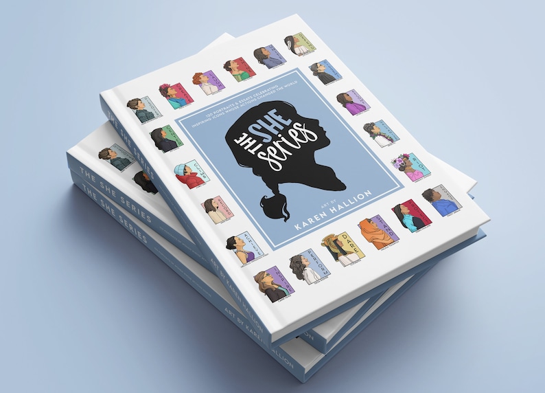 May include: A stack of three white books with blue spines. The top book has the title "The She Series" in blue and white lettering. The book cover features a silhouette of a woman's head with a ponytail and 25 colorful illustrations of women's faces. The text "Art by Karen Hallion" is printed below the silhouette.