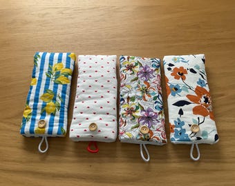May include: Four fabric cases with various patterns. One features blue stripes and lemons, another has red hearts on white, a third has floral designs, and the last has orange and blue flowers. Each case has a wooden button and a loop.