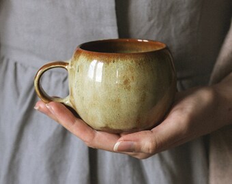 Handmade wheelthrown pottery cozy round mug with handle with warm and earthy looking beige and brown glaze