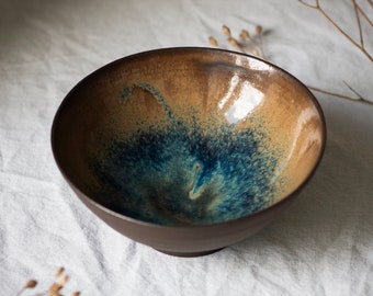 Handmade unique wheelthrown pottery bowl from dark stoneware with brown and blue glaze on the inside