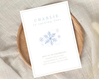 May include: A blue and white invitation card with a snowflake design. The text on the card reads "CHARLIE is turning four" and includes details for a birthday party.