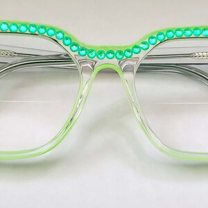 May include: Clear green cat-eye glasses with a row of green rhinestones around the rim.