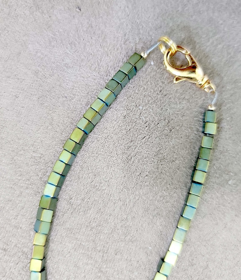 May include: A green and gold beaded necklace with a gold clasp.