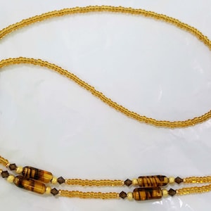 May include: A gold beaded eyeglass chain with brown and gold striped beads and clear crystal accents.