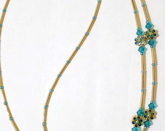 May include: Gold eyeglass chain with turquoise blue flower accents. The chain is made of small gold beads and has two loops at the ends for attaching to glasses.