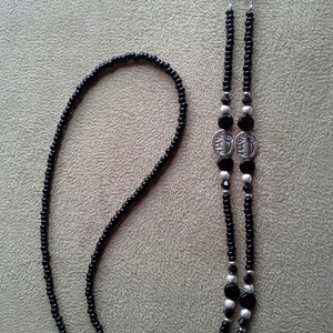 May include: Black beaded eyeglass chain with silver accents. The chain features two silver charms with an elephant design and the words "I Love You" on each charm.