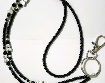 May include: Black beaded lanyard with silver cat charms and a silver swivel clasp.