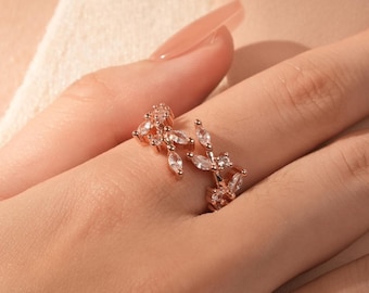 May include: A rose gold ring with a delicate design of leaves and clear cubic zirconia stones.