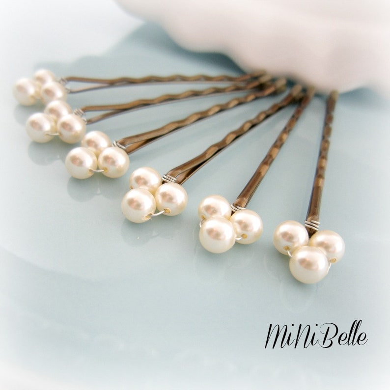 May include: Set of six silver bobby pins with three white pearl accents on each pin.