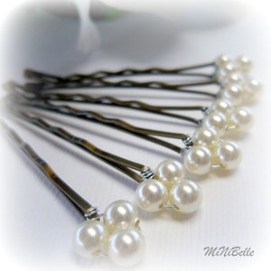 May include: A set of ten silver bobby pins with white pearl accents. Each pin has three pearls clustered together at the end.