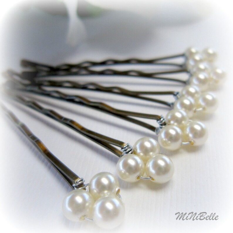 May include: A set of ten silver bobby pins with white pearl accents. Each pin has three pearls clustered together at the end.