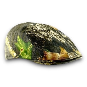 May include: A camouflage print flat cap in shades of green, brown, and white. The hat features a classic, rounded shape with a small, stiff brim. The fabric has a detailed pattern resembling a forest environment.